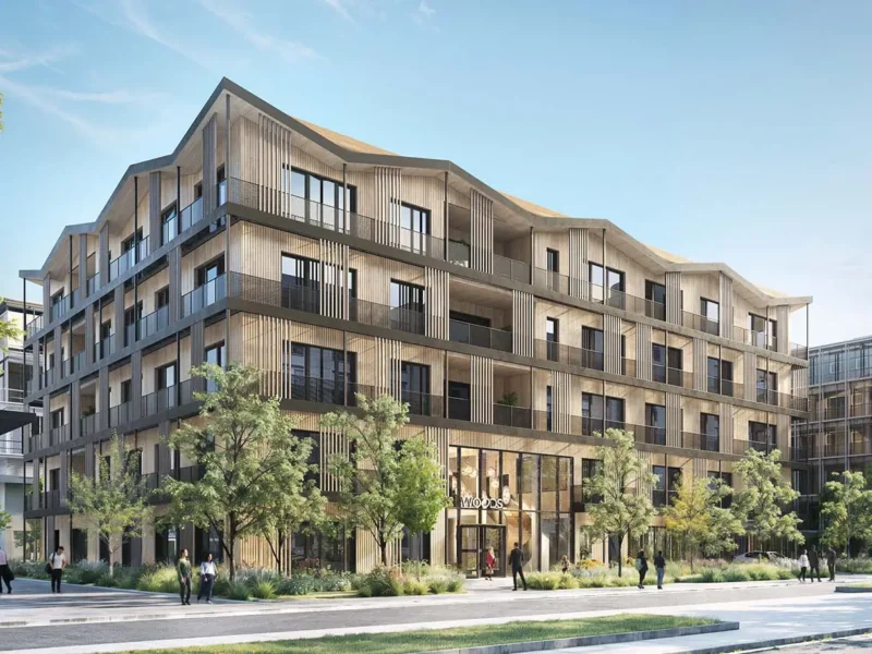Fünfgeschossiges Holzgebäude mit geschwungener Dachkante und vertikalen Holzlamellen an einer baumbestandenen Straße